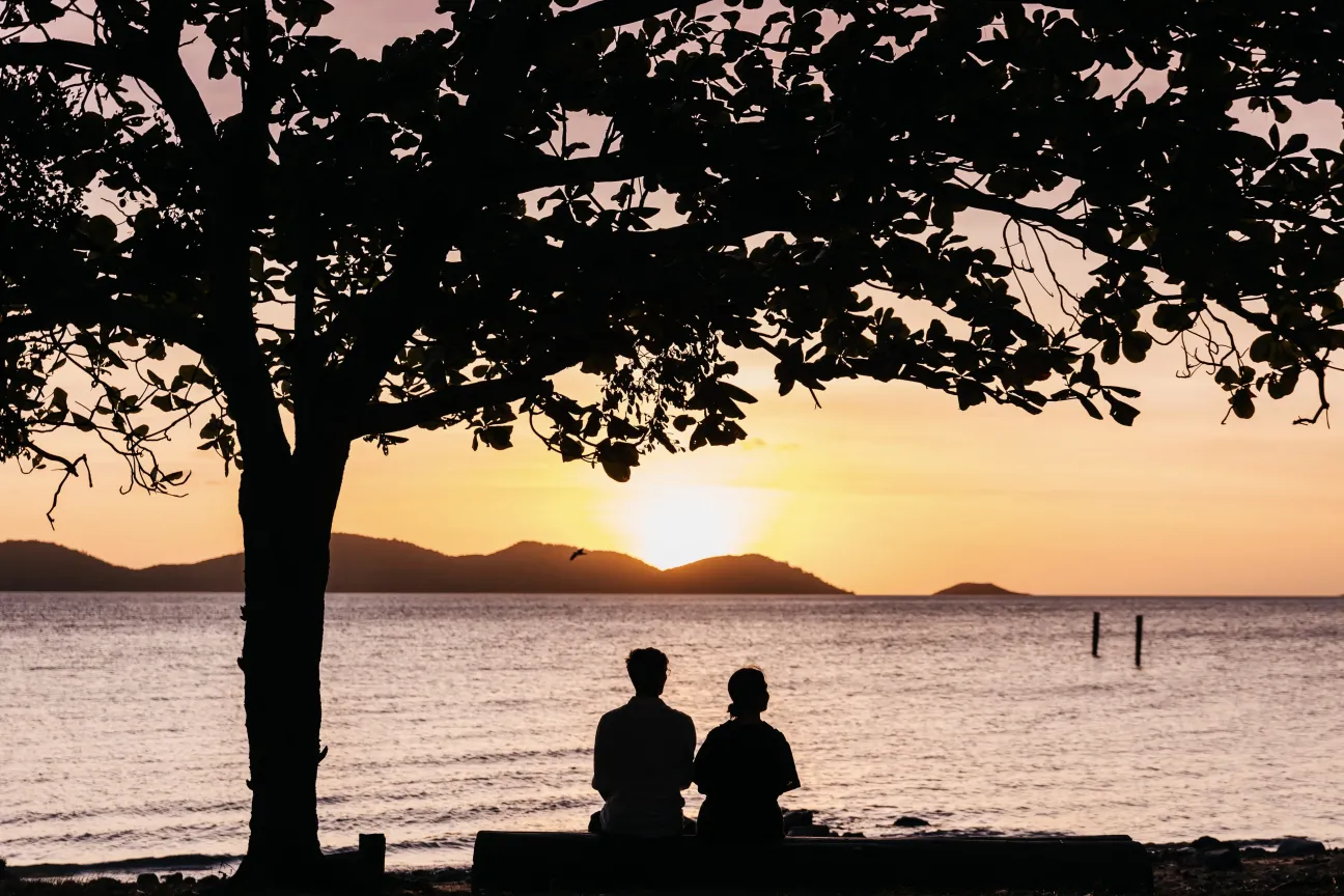 Sunset photo at Bach Beach, Thursday Island, with a couple silhouetted under a tree.